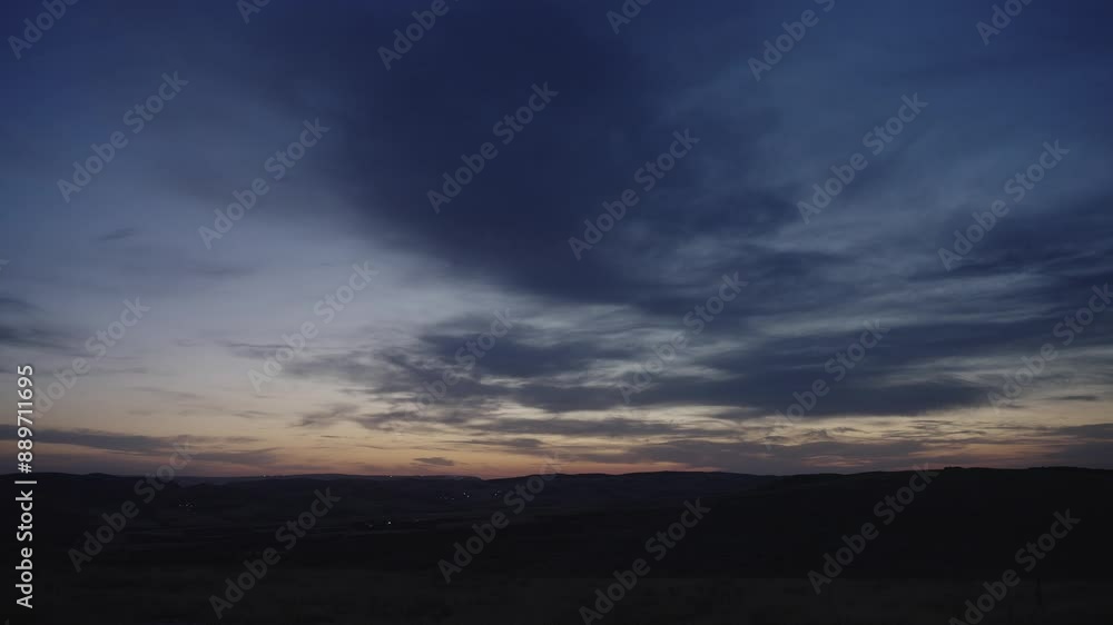 Moving clouds and the lights of the village in the distance as it gets dark Moving clouds and the lights of the village in the distance as it gets dark