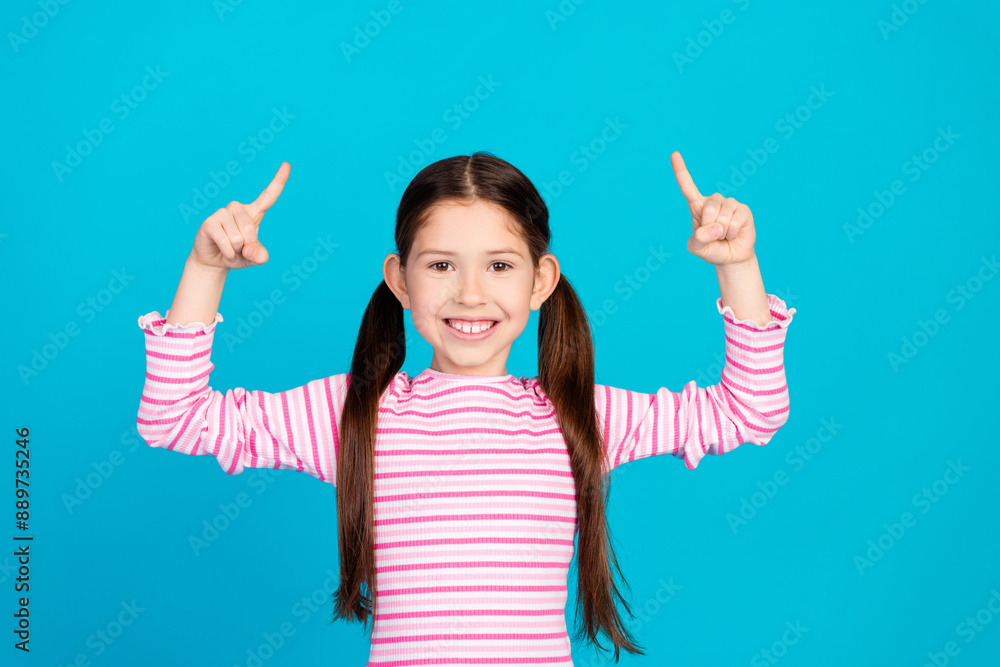 Photo of cheerful small girl with ponytails dressed striped shirt directing at proposition empty space isolated on blue color background Photo of cheerful small girl with ponytails dressed striped shirt directing at proposition empty space isolated on blue color background