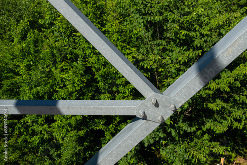 Bolted connections of steel elements of the observation tower. Construction details of galvanized steel against a green trees background