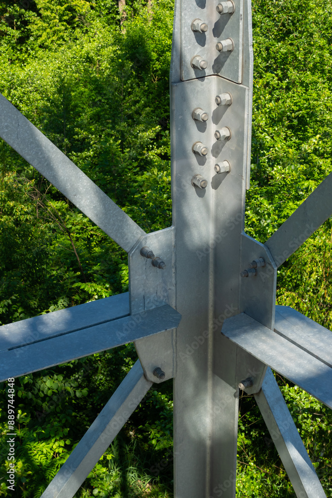 Bolted connections of steel elements of the observation tower. Construction details of galvanized steel against a green trees background