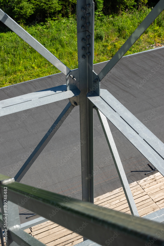 Bolted connections of steel elements of the observation tower. Construction details of galvanized steel against a grey asphalt road surphace