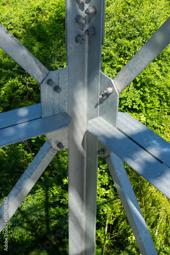 Obraz na płótnie Bolted connections of steel elements of the observation tower. Construction details of galvanized steel against a green trees background w salonie