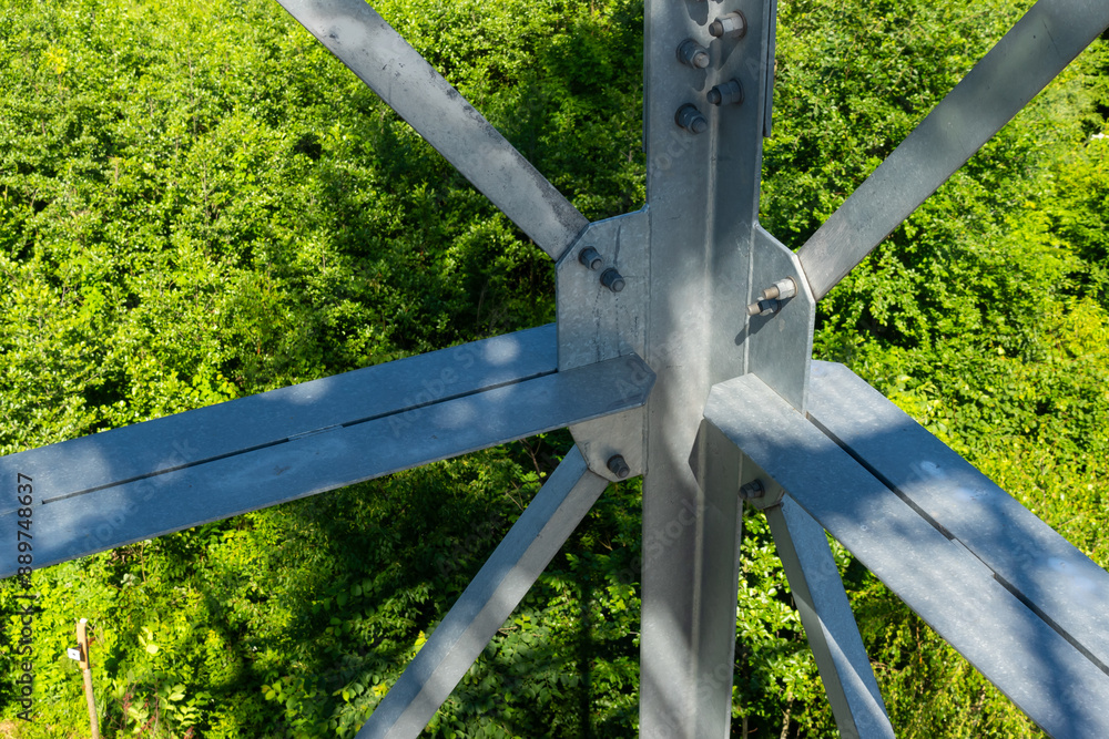 Bolted connections of steel elements of the observation tower. Construction details of galvanized steel against a green trees background