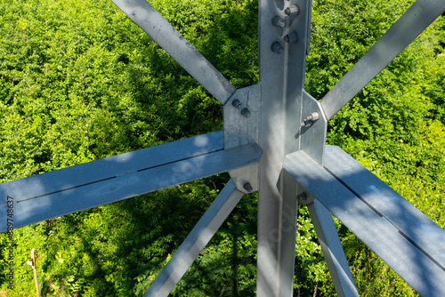 Obraz na płótnie Bolted connections of steel elements of the observation tower. Construction details of galvanized steel against a green trees background w salonie