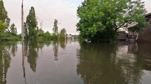 Flooded streets in Kherson town with beautiful sunset at background. Explosion of dam on Dnipro river in city of Novaya Kakhovka. Consequences of detonation of Kakhovka Hydroelectric Power Station photo