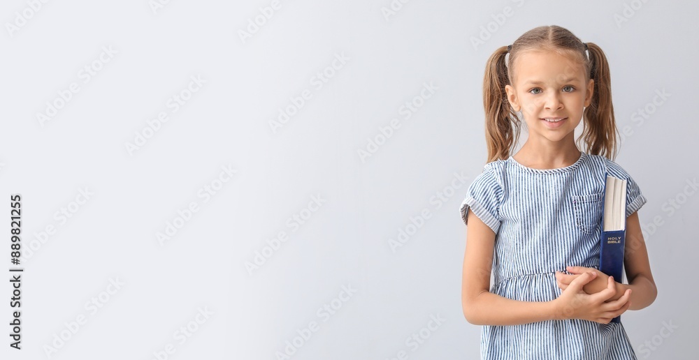 Cute little girl with Bible on light background with space for text Cute little girl with Bible on light background with space for text