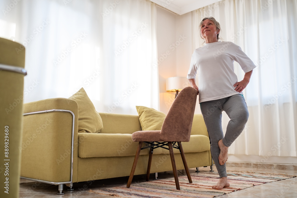 Senior caucasian woman doing yoga at home on chair Senior caucasian woman doing yoga at home on chair