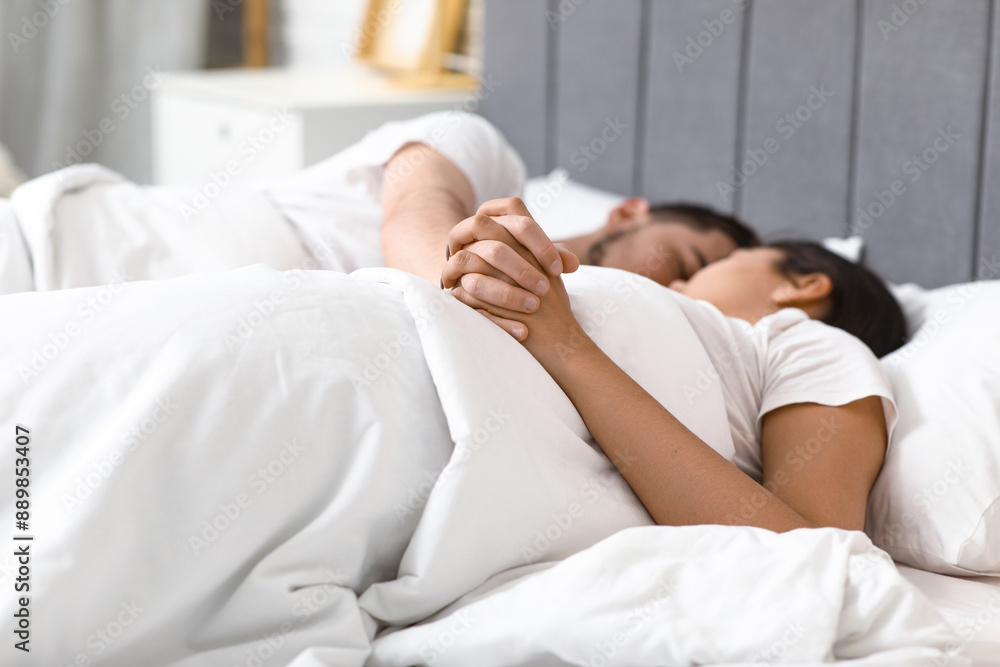Asleep young couple holding hands in bed at home, closeup Asleep young couple holding hands in bed at home, closeup