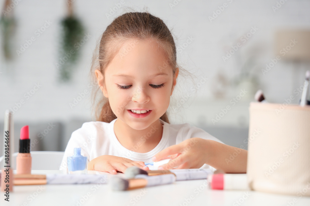 Cute little girl applying nail polish at table in living room Cute little girl applying nail polish at table in living room