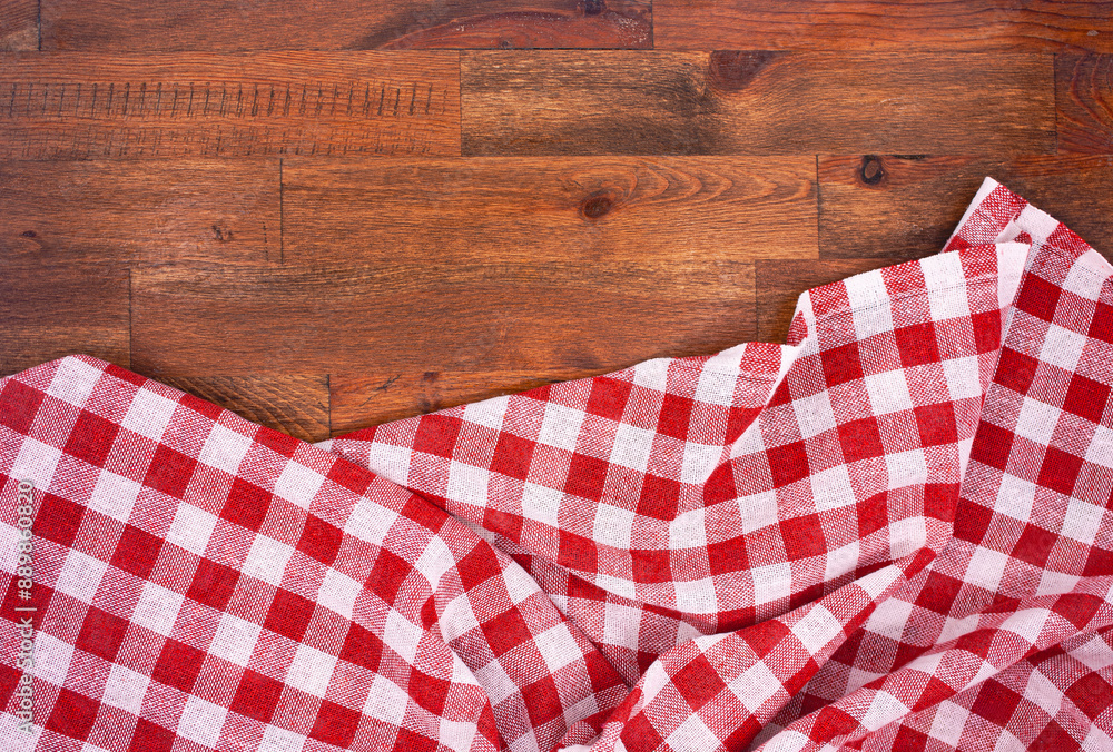 Obraz premium Red and white checkered, plaid tablecloth on wooden surface. Top view. Photograph.