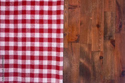 Red and white checkered, plaid tablecloth on wooden surface. Top view. Photograph.
