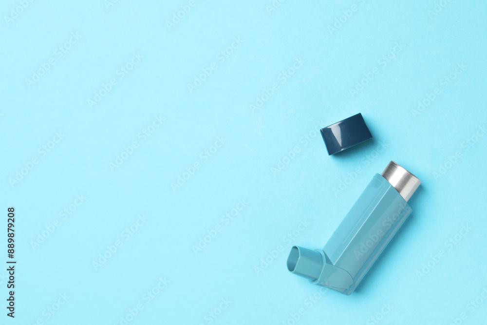 Fototapeta premium Asthma inhaler on light blue background, top view. Space for text