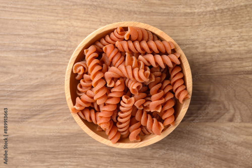 Raw fusilli pasta in bowl on wooden background, Table top view