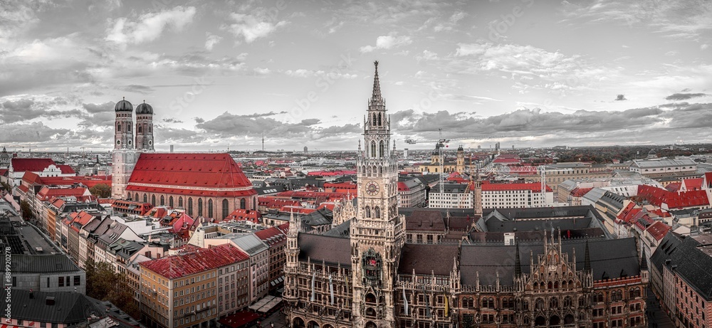Fototapeta premium A view of the city of Munchen, Germany, from above with the spires and towers of the city's churches and buildings standing tall against a cloudy sky.