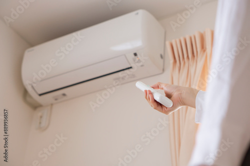 A woman turning on the air conditioner. Person turning off the air conditioner.  エアコンのスイッチをつける女性。エアコンのスイッチを消す人。