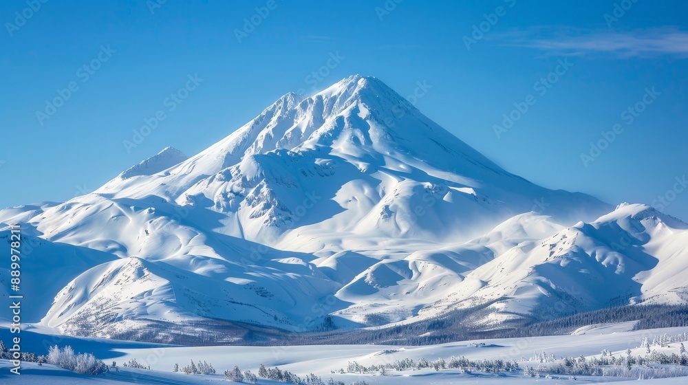 A snow-covered mountain peak against a clear blue sky, with the surrounding landscape blanketed in white A snow-covered mountain peak against a clear blue sky, with the surrounding landscape blanketed in white