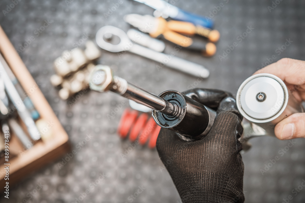 Mechanic holding motorcycle rear shock absorber old and leak , Replace shock absorbers seals in garage, maintenance and repair concept.