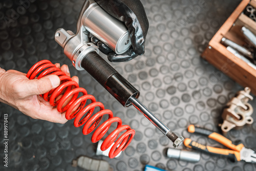 Mechanic holding motorcycle rear shock absorber old and leak , Replace shock absorbers seals in garage, maintenance and repair concept
