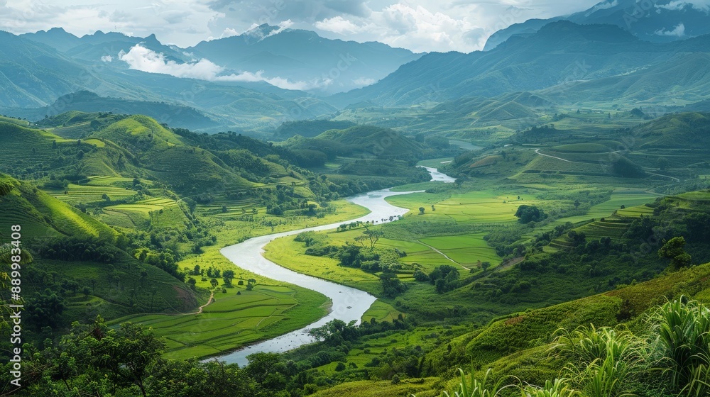 Fototapeta premium A stunning view of a winding river cutting through a lush green valley, with mountains in the background