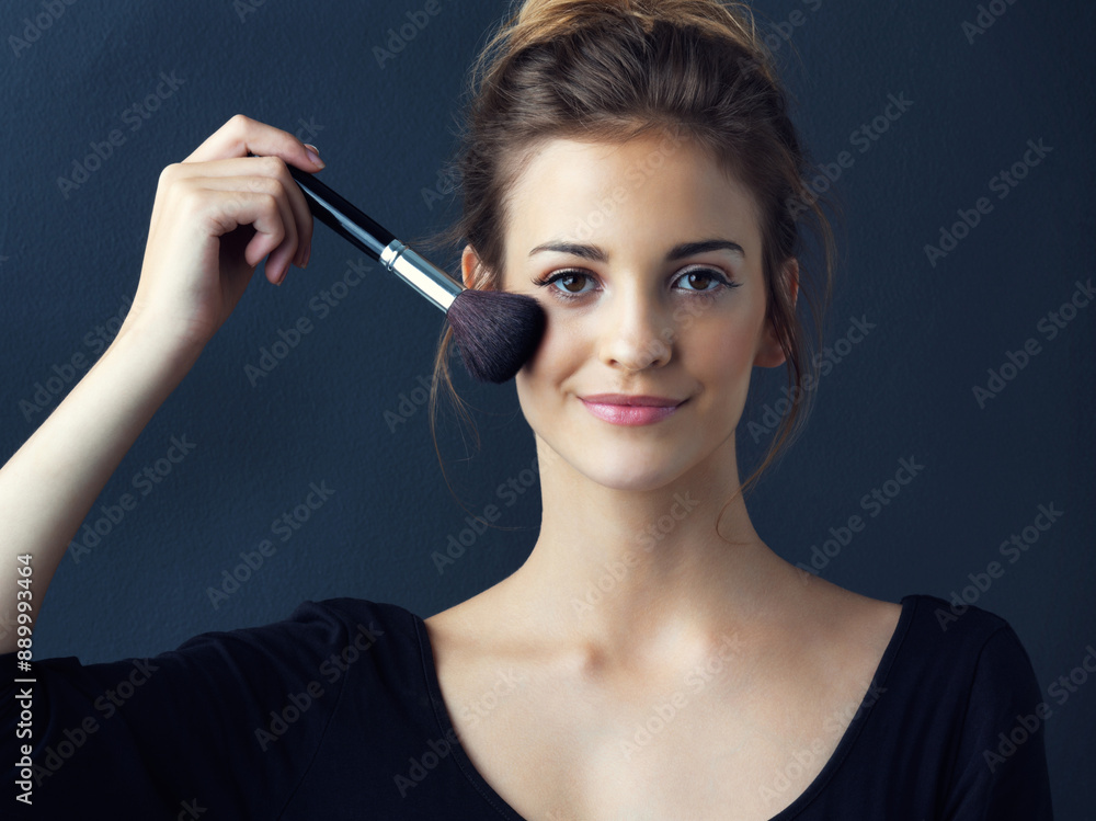 Obraz premium Happy woman, portrait and beauty with makeup brush for foundation or blush on a blue studio background. Young female person or model with smile in facial treatment for cosmetics, glow up or shine