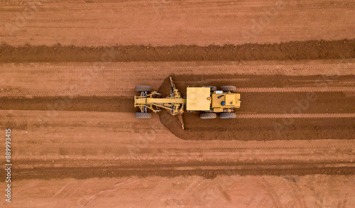 Aerial view road motor grader flatting dirt road surface, Motor grader road construction grader industrial machine on construction site of new road. photo