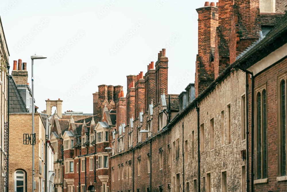A narrow street in Cambridge, UK lined with brick buildings and chimneys. A narrow street in Cambridge, UK lined with brick buildings and chimneys.