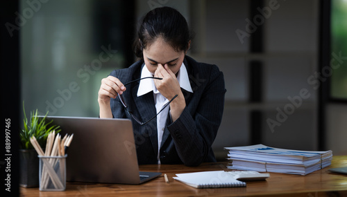 Tired asian businesswoman with headache at office, feeling sick at work, copy space