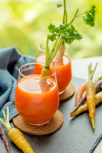 Two glasses of carrot juice and fresh carrots on the table. Concept: diet, healthy eating, food, and weight loss photo