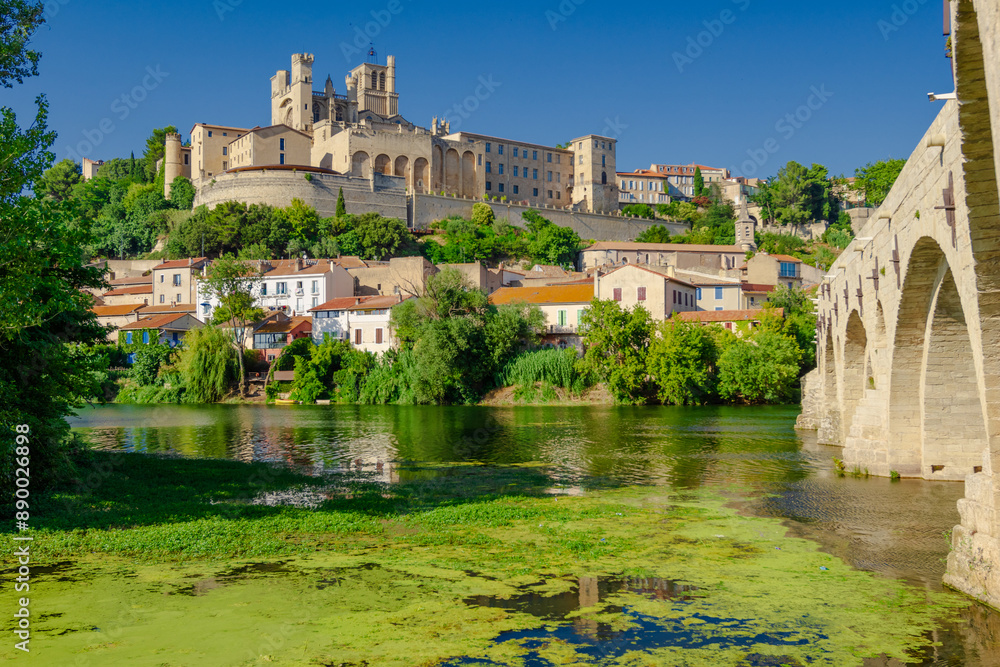 Fototapeta premium Cathedral Saint-Nazaire-A river runs through a town with a castle in the background