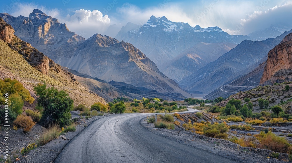 Fototapeta premium Highway winding through rugged mountains with greenery and dramatic cloudy sky