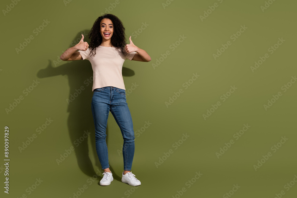 Full size photo of satisfied adorable girl dressed beige t-shirt jeans showing thumbs up good job isolated on khaki color background Full size photo of satisfied adorable girl dressed beige t-shirt jeans showing thumbs up good job isolated on khaki color background