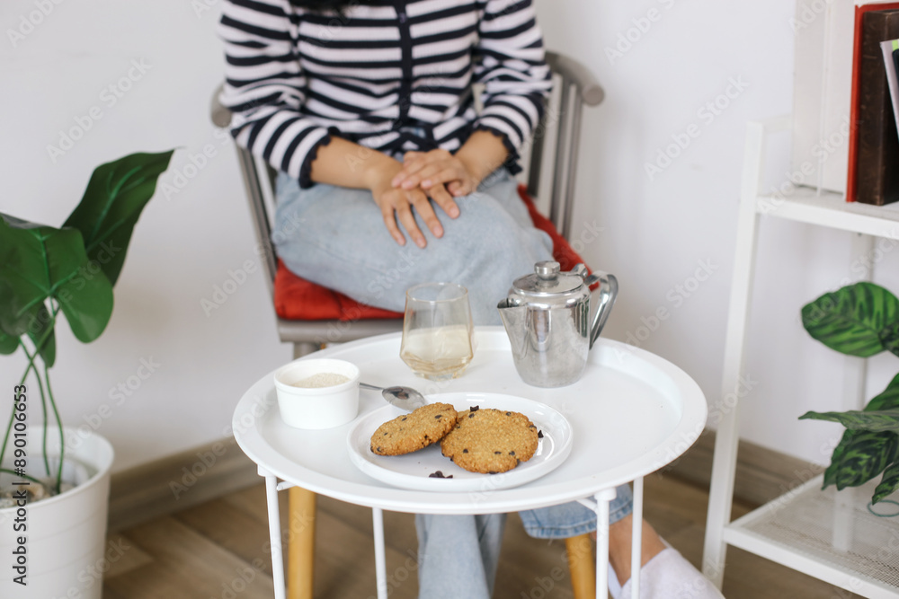 Selective Focus Cookies With Sugar, Glass Cup And Tea Pot Against Woman Sitting Background Selective Focus Cookies With Sugar, Glass Cup And Tea Pot Against Woman Sitting Background