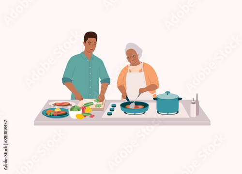 Smiling Black Older Mother In Apron Cooking Steak With Frying Pan. Adult Son Helping His Mum To Cut The Cucumber.