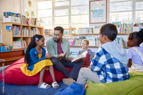 Fotografía Teacher reading book to his little students in a library
