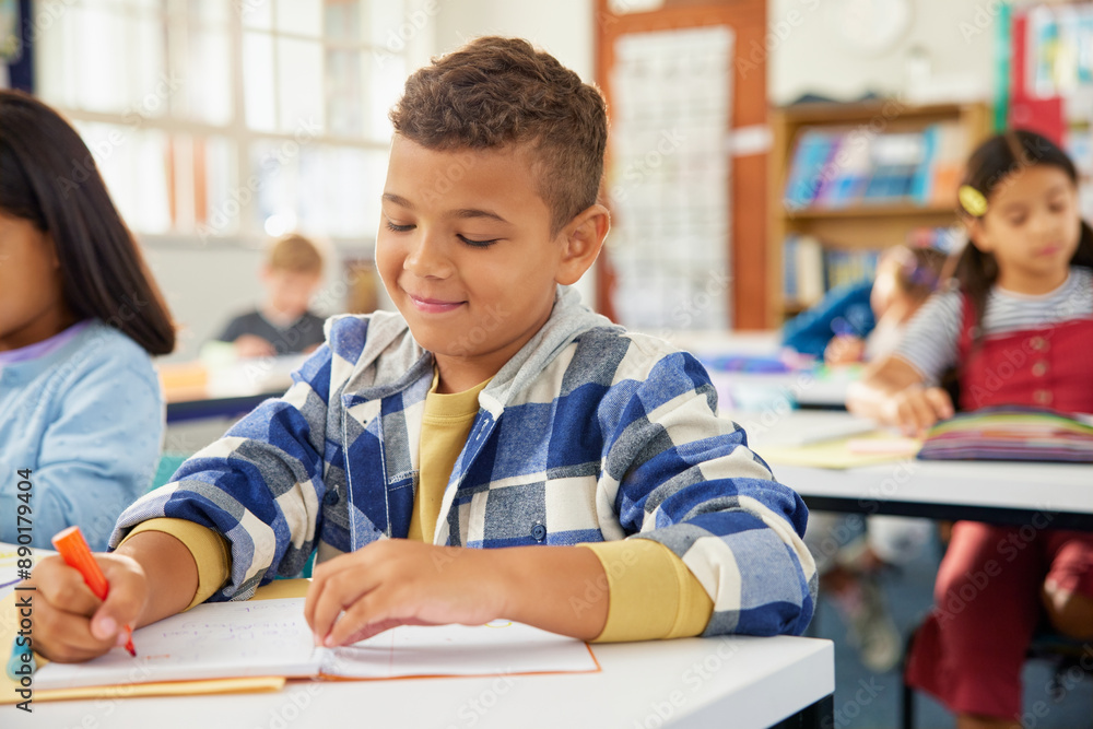 Mixed race school boy writing in primary classroom during test Mixed race school boy writing in primary classroom during test