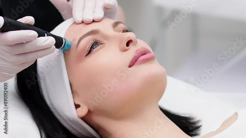 A cosmetologist does a hydrofacial procedure on a woman's face in a modern beauty clinic. Concept of cosmetology, care and healthy skin. photo