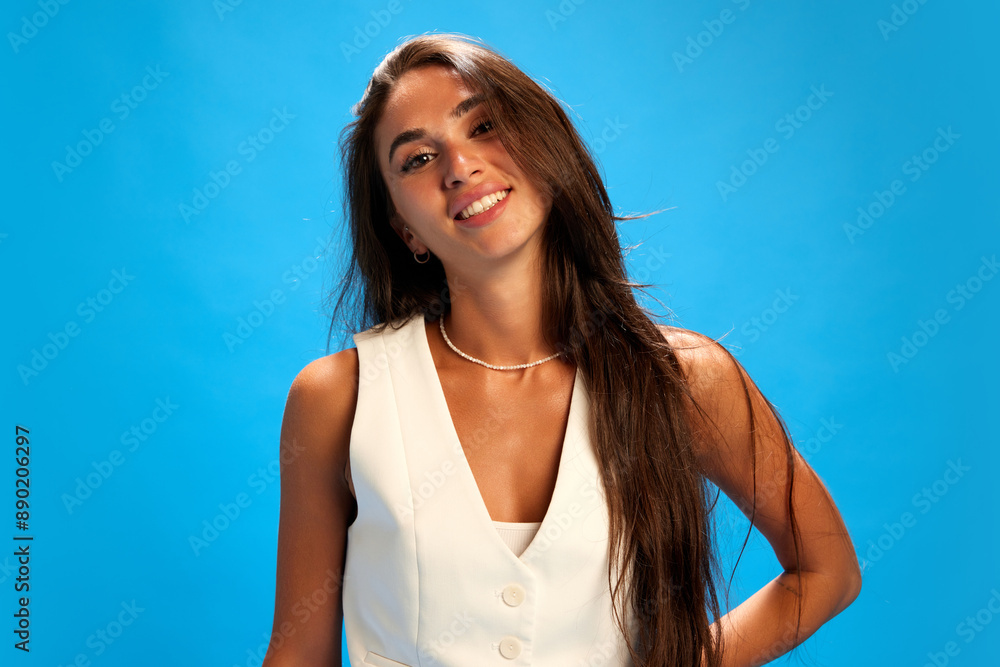 Beautiful, smiling young woman dressed casual attire looking at camera against blue studio background. Trendy colors. Concept of human emotions, fashion and style, business. Beautiful, smiling young woman dressed casual attire looking at camera against blue studio background. Trendy colors. Concept of human emotions, fashion and style, business.