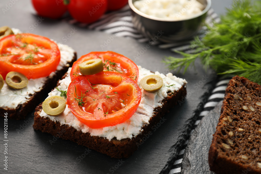 Delicious ricotta bruschettas with sliced tomatoes, olives and greens on black table, closeup Delicious ricotta bruschettas with sliced tomatoes, olives and greens on black table, closeup