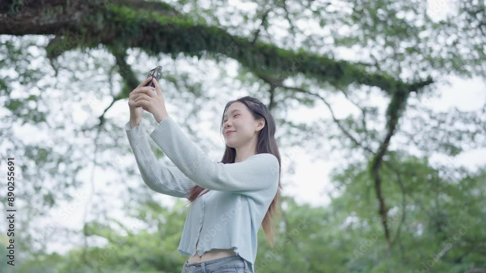 Asian woman using smartphone in park in sunny day Asian woman using smartphone in park in sunny day