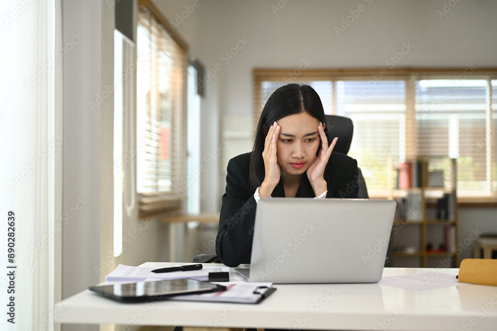 Youn businesswoman experiencing stress while working on her laptop in a modern home office Youn businesswoman experiencing stress while working on her laptop in a modern home office