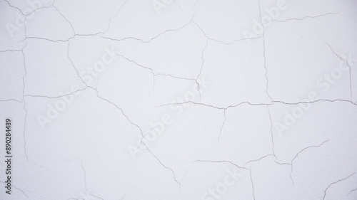 Wallpaper texture for background and design. Peeling paint on the wall. White concrete wall with old cracked flaking paint. Weathered rough painted surface with patterns of cracks.