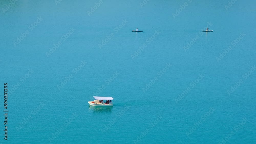 People enjoy pedal boating and and standup paddleboarding in the clear blue turquoise waters People enjoy pedal boating and and standup paddleboarding in the clear blue turquoise waters