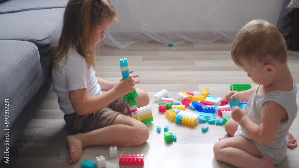 Baby boy and little girl building tower of block toys. Kids playing with colorful toy blocks. Educational and creative toys and games for brother and sister. Children in bedroom with rainbow bricks Baby boy and little girl building tower of block toys. Kids playing with colorful toy blocks. Educational and creative toys and games for brother and sister. Children in bedroom with rainbow bricks