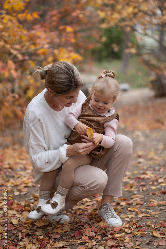 young beautiful mother holding toddler's daughter her arms fall autumn leaves. long-awaited motherhood. beloved mother and daughter. upbringing of a child. single mother. social allowance for childcar young beautiful mother holding toddler's daughter her arms fall autumn leaves. long-awaited motherhood. beloved mother and daughter. upbringing of a child. single mother. social allowance for childcar