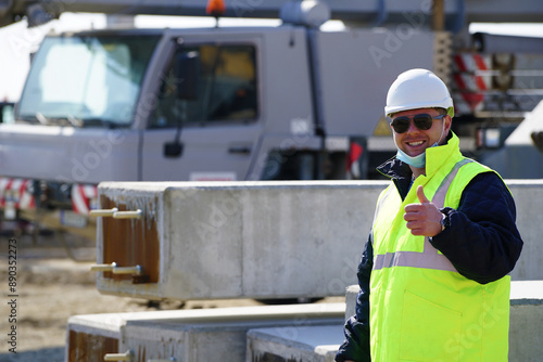 Portrait of young architect with reflective clothing on construction site and with a mask and excavator on the background 