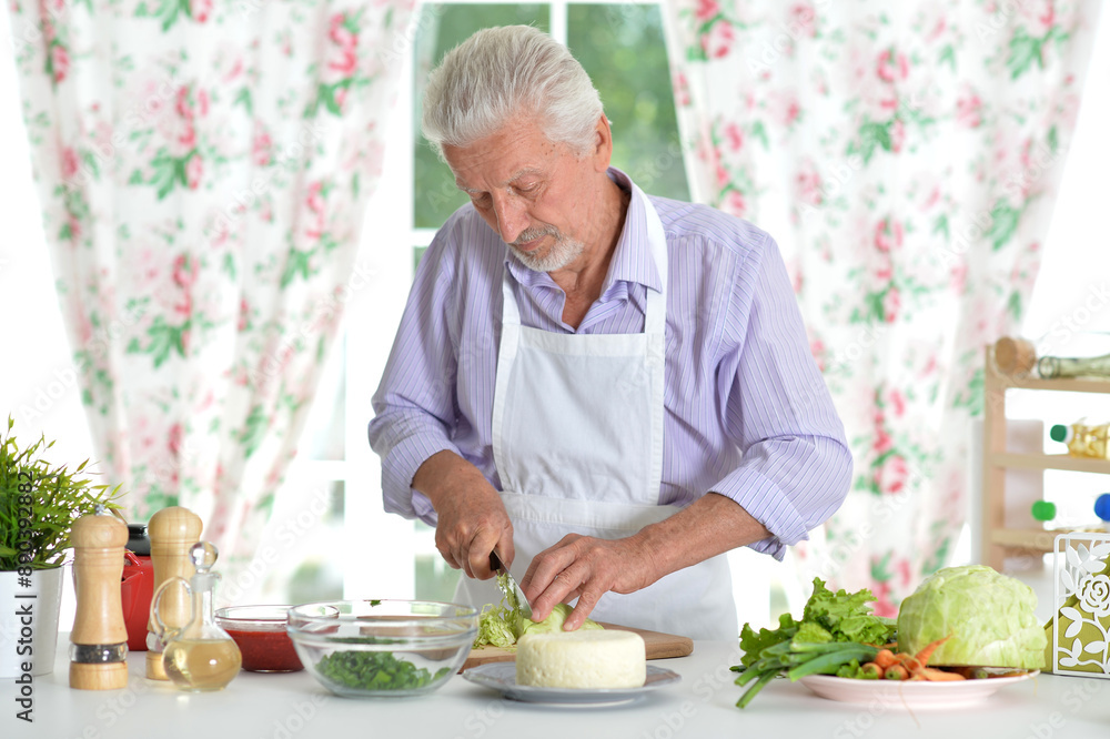 Happy retired senior man cooking in kitchen. Happy retired senior man cooking in kitchen.