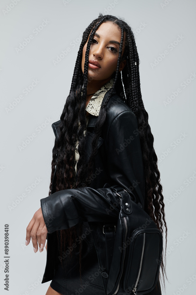A young African American woman poses in a black leather jacket and skirt, an animal print shirt peeking out from under the collar.