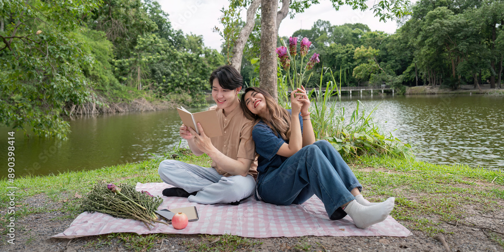 Happy Couple Relaxing Outdoors by a Lake, Reading and Enjoying Nature on a Picnic Blanket