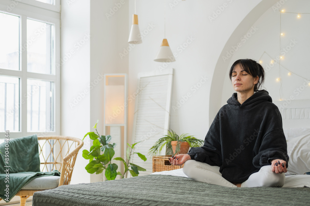 Yoga mindfulness meditation. Young healthy woman practicing yoga in bedroom at home. Woman sitting in lotus pose on bed meditating smiling relaxing indoor. Girl doing breathing practice. Yoga at home Yoga mindfulness meditation. Young healthy woman practicing yoga in bedroom at home. Woman sitting in lotus pose on bed meditating smiling relaxing indoor. Girl doing breathing practice. Yoga at home