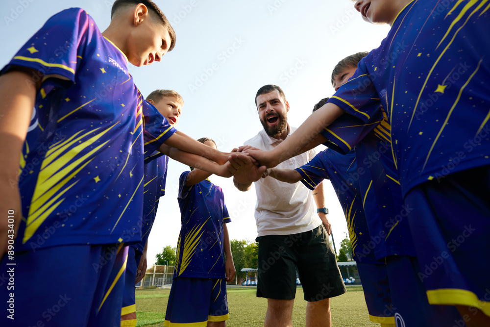 Fototapeta premium Young soccer players and their coach unite with hands in, showing team spirit and enthusiasm. Motivation before game. Concept of sport, childhood, education, achievement, active lifestyle